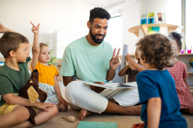 A person sitting on the floor reading a book with children