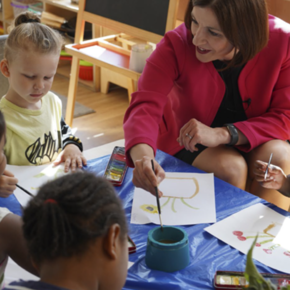 The Secretary of State for Education sits with young children helping them paint