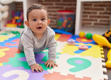 A toddler crawling on a colourful foam play mat.