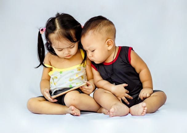 Two young children sitting together and staring a tablet