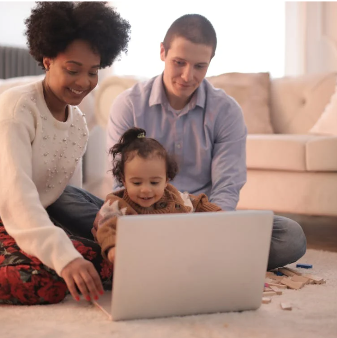 Family sitting on floor while using a laptop