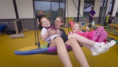 A person and two children on a swing