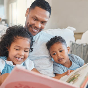 An adult and two children reading a book together