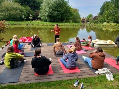 A group of people sitting on mats by a lake