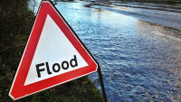 Flood sign next to flooded road