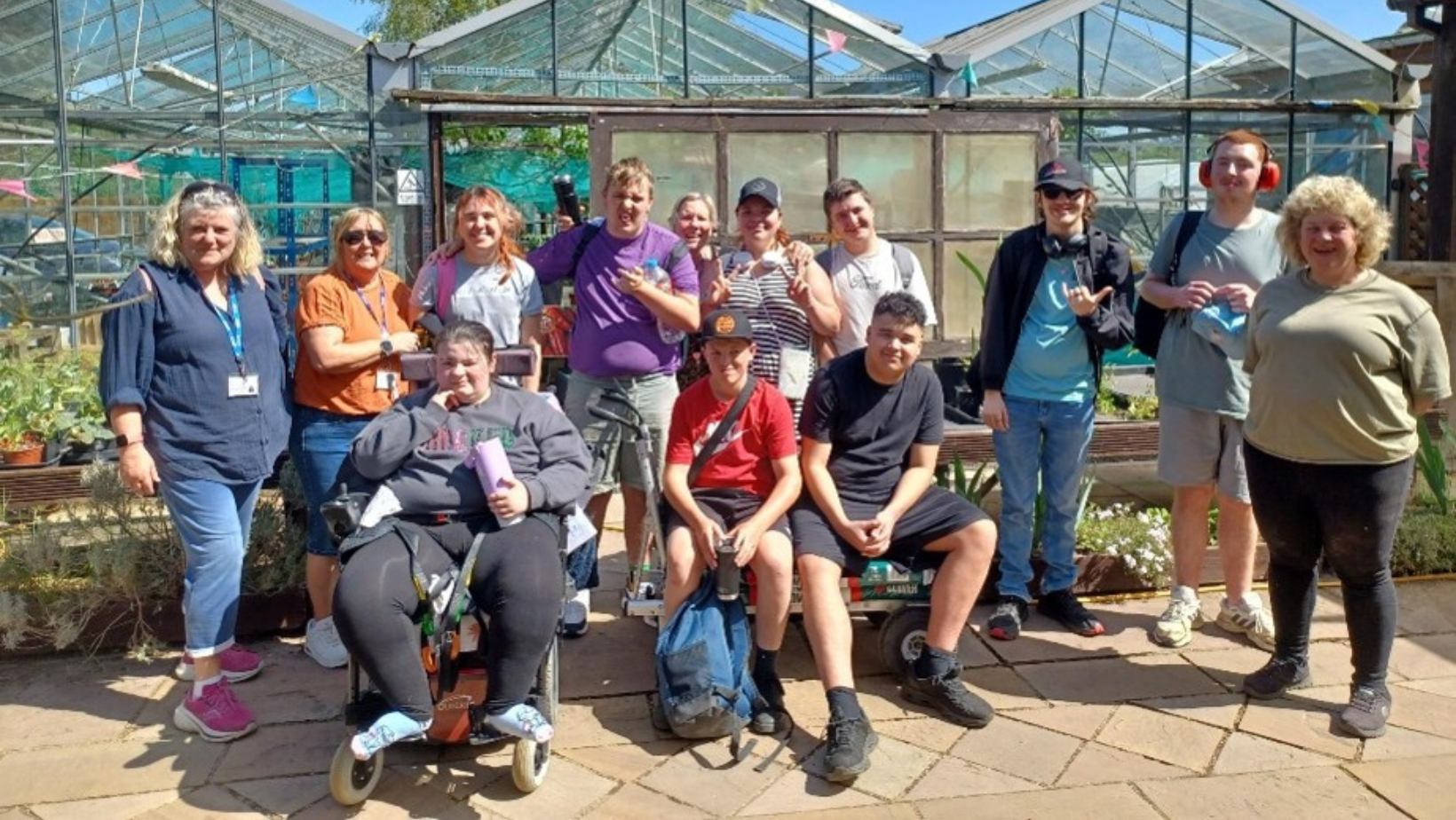 Youth Impact team and young people of varying ages standing in a group in front of a greenhouse