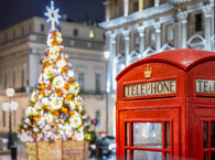 The top of a red London telephone box in the foreground, with a brightly lit Christmas tree behind.