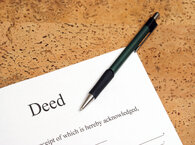 A document titled 'Deed' with a pen laid across it.