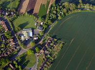 An aerial view of a large building set in its own grounds and surrounded by fields.