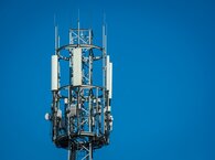 The top of a telecommunications tower viewed against a blue sky.