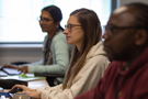 Three caseworkers sitting side by side on a row of desks look intently at their screens.