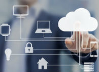 A man in a suit standing behind a transparent screen points to an icon of a cloud on the screen, with the cloud connected to various other technology and property-related icons.