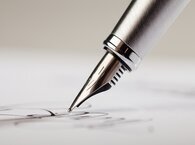 The nib of a fountain pen poised above a sheet of paper.