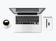 An open laptop viewed from above, with a coffee cup on its left and a notebook and pen on its right.