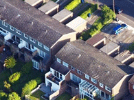 Terraced housing, viewed from above, with driveways in front and gardens behind,