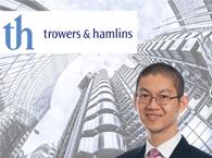 A head and shoulders photo of a Trowers & Hamlins lawyer with a background of a City of London skyscraper and the company logo.