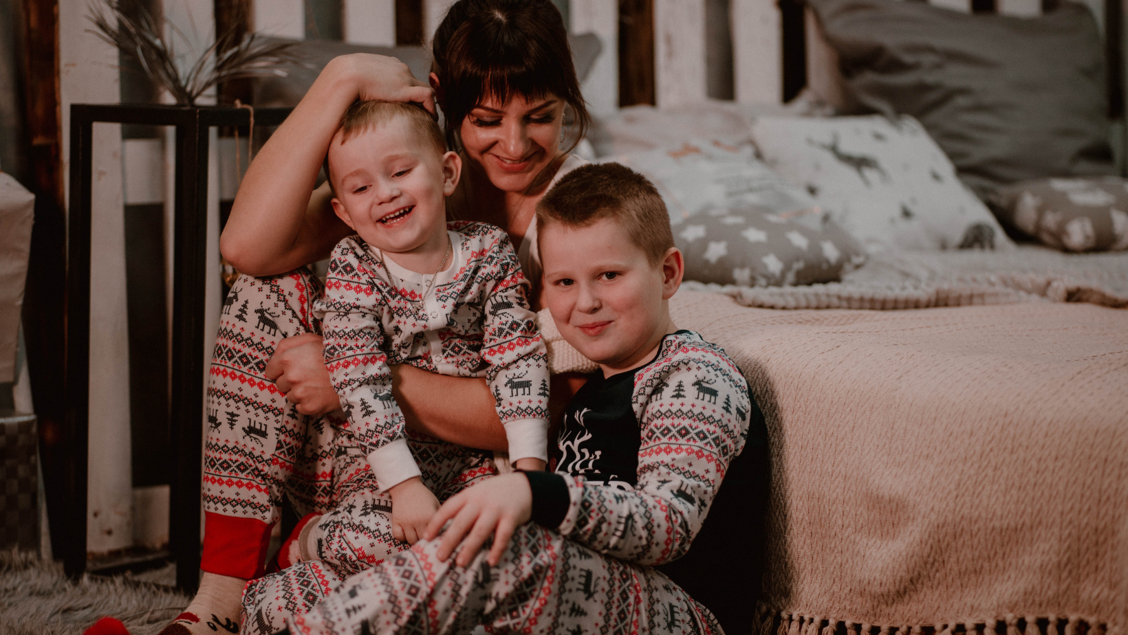 An image of a mother with her 2 sons who are both in Christmas pyjamas